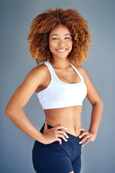 Te queda bien lo saludable. una joven deportista posando sobre un fondo gris - Foto, Imagen