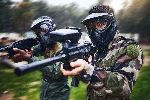 Training, paintball gun and men in camouflage with safety gear at military game for target practice. Teamwork, shooting sports and war games, play with rifle and friends working together at army park. - 写真・画像