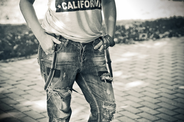 Figura feminina close-up: jeans rasgado usado com suspensórios, camisa, uma pulseira no braço
 - Foto, Imagem
