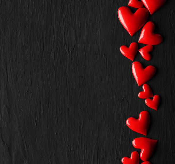 Колекція блискучих червоних сердець на темному грубому фоні
 - Фото, зображення