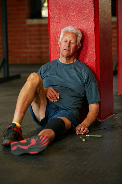 Sommige trainingen zijn moeilijker dan andere. een oudere man die een pauze neemt van een vermoeiende training - Foto, afbeelding