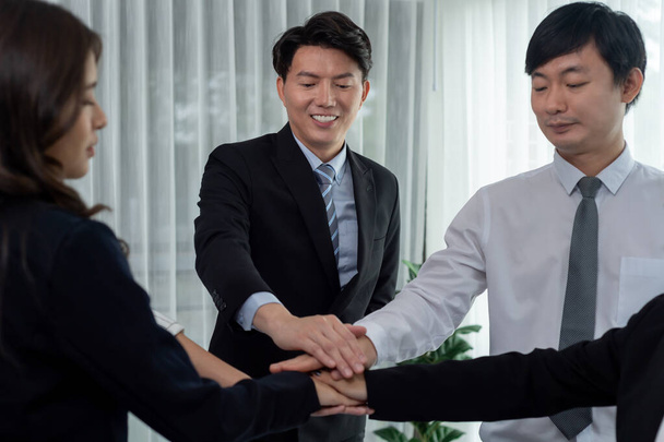Closeup business team of suit-clad businessmen and women join hand stack together and form circle. Colleague collaborate and work together to promote harmony and teamwork concept in office workplace. - Foto, Imagem
