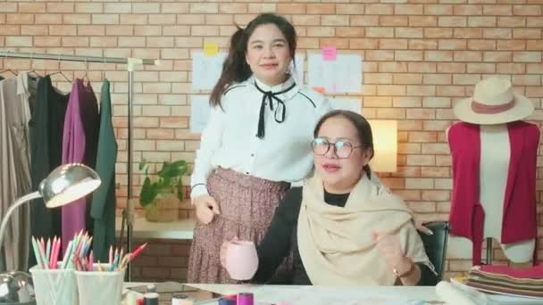Asian middle-aged female fashion designer and young teen trainee tailor celebrate and cheerful with dress design work success and satisfy in stylist studio, happy costume boutique small business.  - Footage, Video