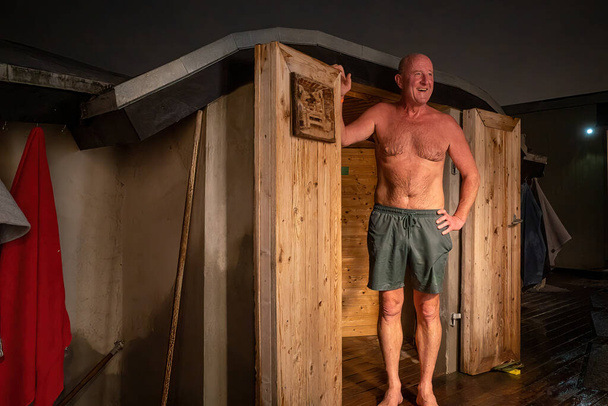 Copenhagen, Denmark A man stands outside a door leading to a warm sauna. - Fotoğraf, Görsel
