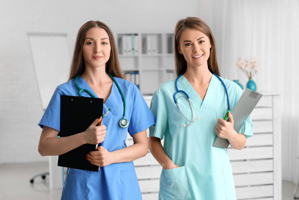 Female medical assistants with clipboards in clinic - Zdjęcie, obraz