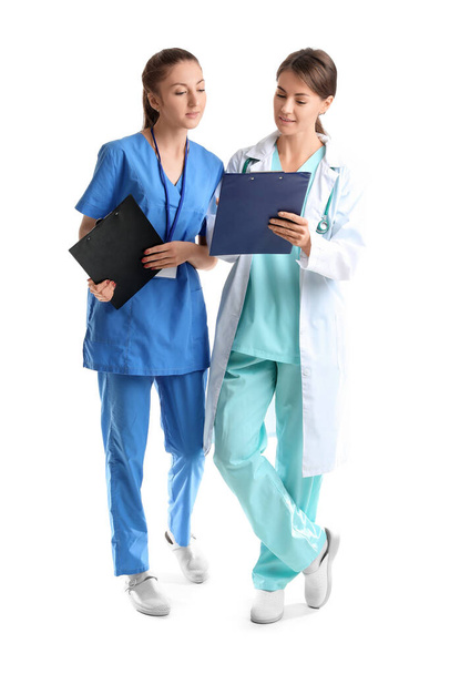 Female doctor and intern with clipboards on white background - Foto, Imagem