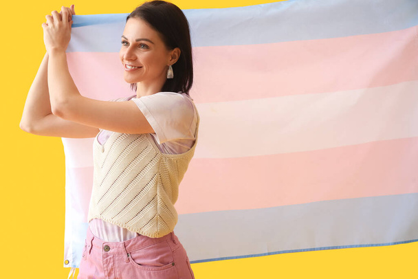 Красива жінка з трансгендерним прапором на жовтому тлі
 - Фото, зображення