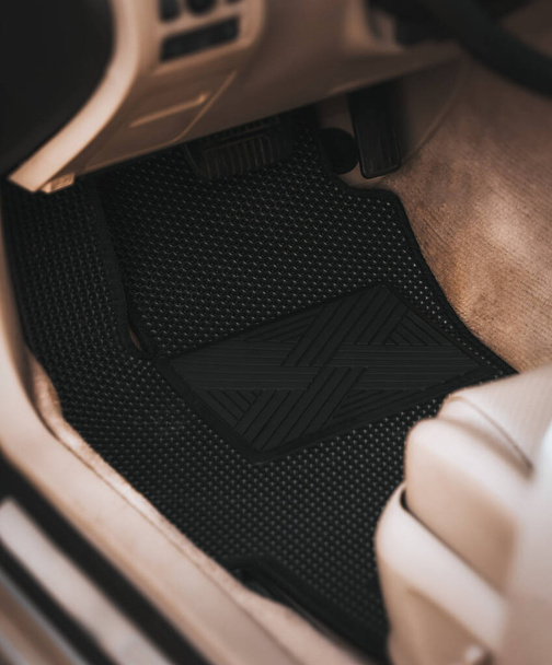Водительские коврики на черном полу из этиленвинилацетата сокращены для EVA. Темные коврики в светлом салоне автомобиля. - Фото, изображение