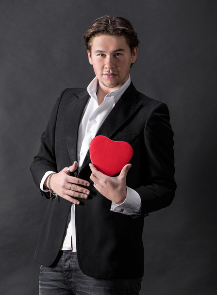 Young handsome man holding red heart - Fotó, kép