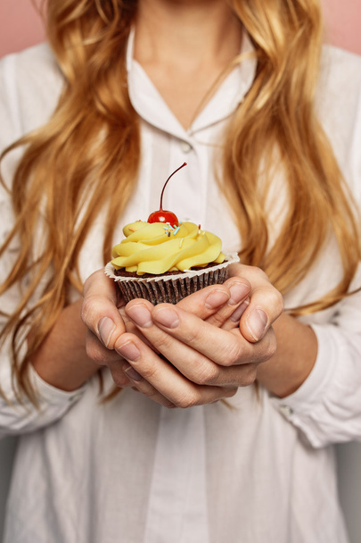attraktives Mädchen im weißen Hemd hält Cupcakes in der Hand - Foto, Bild