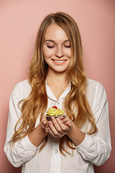 Atractiva chica en una camisa blanca está sosteniendo cupcakes
 - Foto, imagen