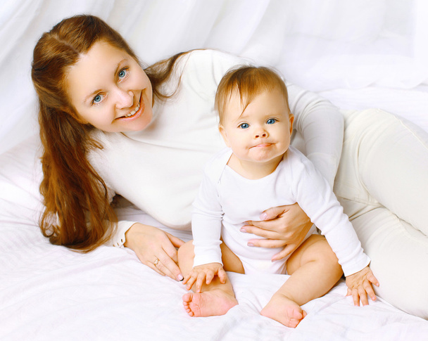 Szép boldog anya és a baba szórakozás az ágyban otthon - Fotó, kép