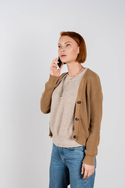Redhead woman in casual clothes talking on smartphone isolated on grey  - Valokuva, kuva