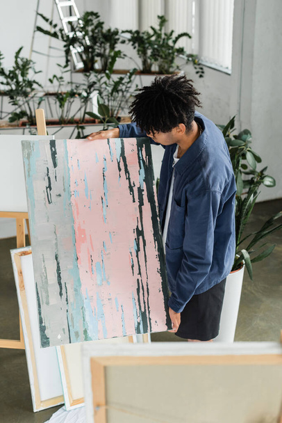 Young african american artist looking at drawing in studio  - 写真・画像
