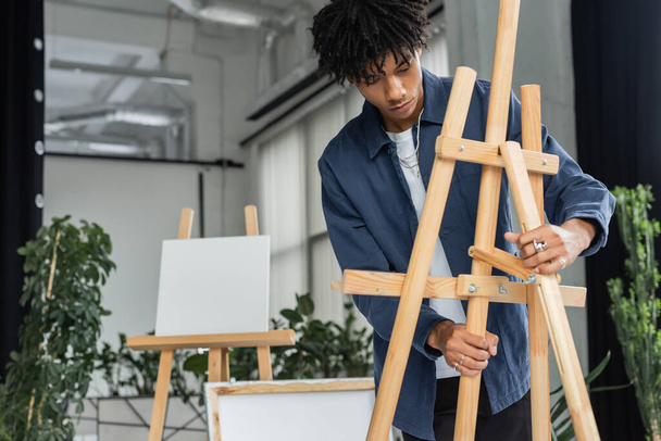 Young african american artist regulating easel in studio   - Photo, Image