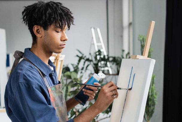 Afričtí američtí umělci v zástěře malba na bílém plátně ve studiu  - Fotografie, Obrázek