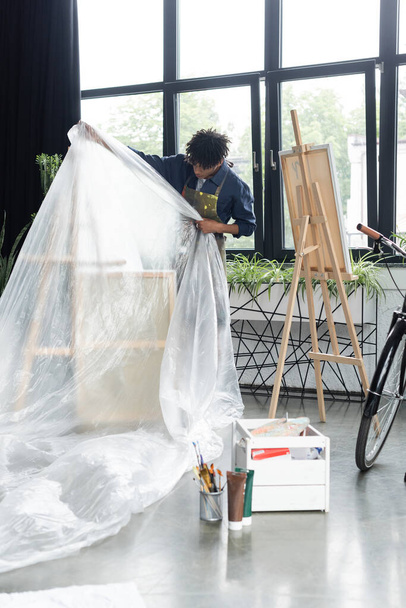 Afrikai amerikai művész tesz celofán állványra a stúdióban  - Fotó, kép