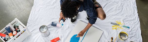 Overhead view of african american artist painting on canvas on floor in workshop, banner  - Photo, Image