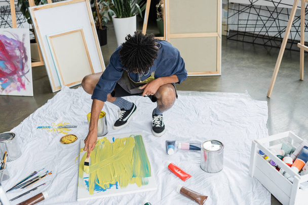 Αφρο-Αμερικανός καλλιτέχνης ζωγραφική σε καμβά σε ύφασμα στο στούντιο τέχνης  - Φωτογραφία, εικόνα