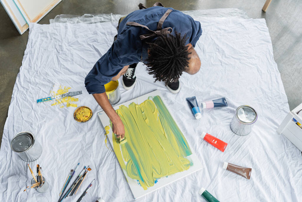 Overhead view of african american artist painting on canvas on floor  - Photo, Image