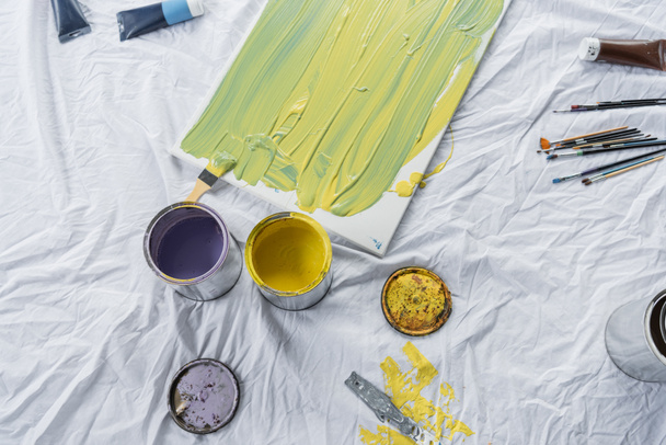 Vista superior de pinturas en tarros y lienzo sobre tela en estudio  - Foto, Imagen