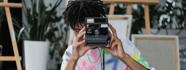 Mladý africký americký umělec fotografování na vintage camera ve studiu, banner  - Fotografie, Obrázek