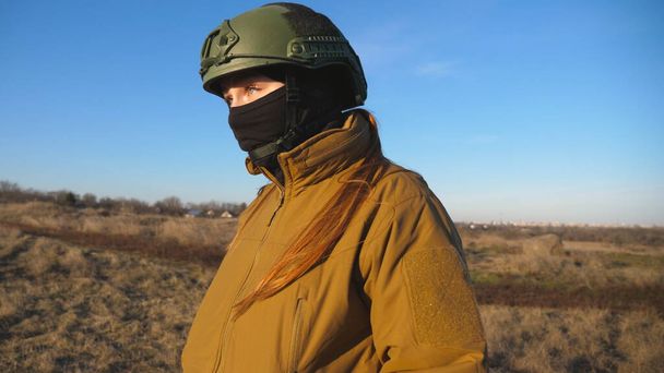 Soldado feminino do exército ucraniano a caminhar no campo. Mulher de uniforme militar e capacete no prado ao pôr-do-sol. Ucrânia vitória contra a agressão russa. Conceito de resistência à invasão. Movimento lento. - Foto, Imagem