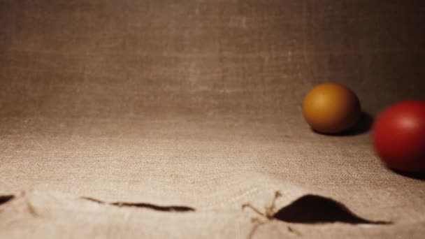 Easter celebrations. Easter Eggs. Brown and red chicken Eggs. Painted Easter Eggs on a Brown Linen Bedspread. An Easter egg rolling on a linen bedspread. - Materiał filmowy, wideo