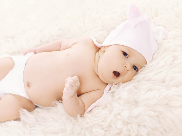 Sweet baby in hat yawns on the bed  - Fotoğraf, Görsel