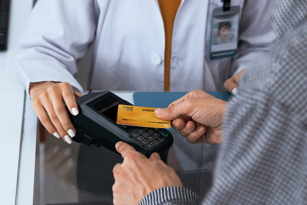 Payment by credit card with payment terminal in qualified drugstore or hospital. Modern payment of electric money. Closeup customer purchase medication in pharmacy with credit card on pos. - Photo, Image
