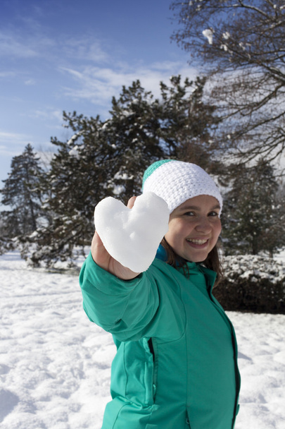 Прекрасна молода жінка показує снігове серце
 - Фото, зображення