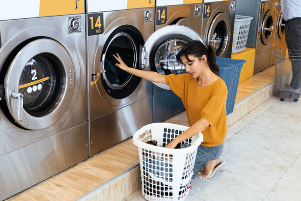 Gli asiatici che utilizzano una lavatrice a gettoni qualificata nella sala comune per lavarsi i panni. Concetto di lavanderia e asciugatrice self-service in un locale pubblico. - Foto, immagini