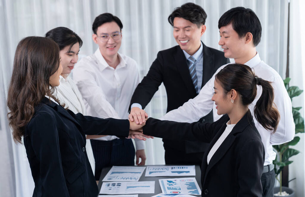 Closeup business team of suit-clad businessmen and women join hand stack together and form circle. Colleague collaborate and work together to promote harmony and teamwork concept in office workplace. - Foto, immagini