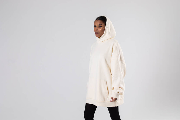 Attractive african american woman in oversized white hoodie. Mock-up. - 写真・画像