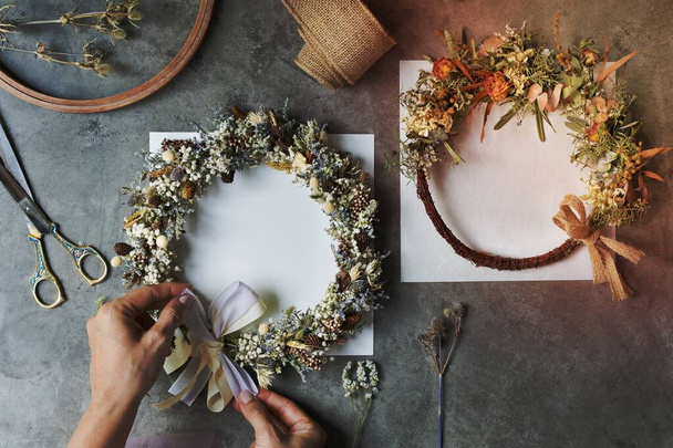 Woman tying a ribbon on a floral wreath - Photo, Image