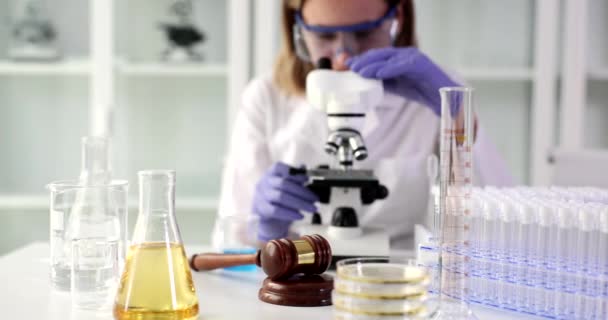 Portrait of scientist who is looking at microscope working on oil and oil chemistry. Research and development of cosmetic anti -aging oils - Séquence, vidéo