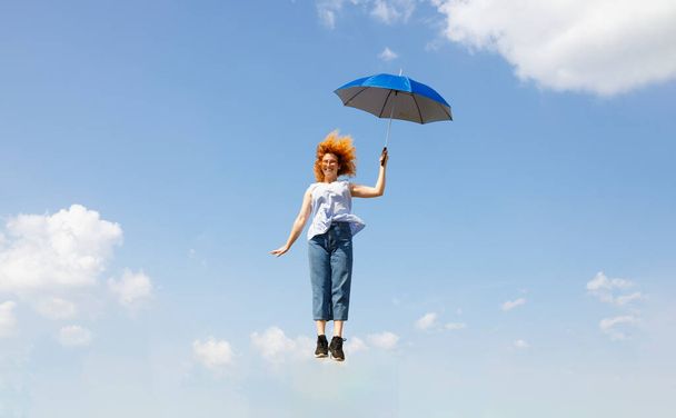 Young woman hopping with an umbrella - Foto, Bild