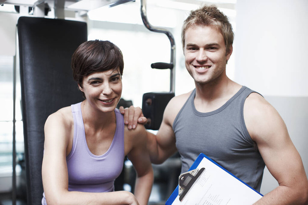 Shes been an awesome client. Cropped portrait of a handsome young man and his personal trainer in the gym - Photo, Image