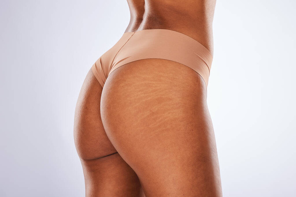 Cellulite, buttocks and underwear with a model black woman in studio on a gray background for body positivity. Stretch marks, real and natural with a female posing in lingerie from the back. - Photo, Image