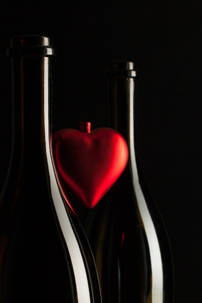 Silhouettes of elegant wine bottles with red heart  - Foto, afbeelding