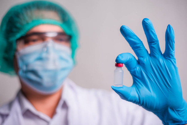 Doctor holding flu vaccine on beige background, medicine and drug concept. Vaccination against Coronavirus covid-19 pandemic. - Φωτογραφία, εικόνα