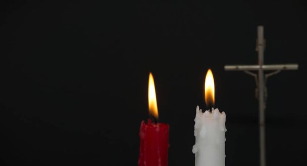 Banner size image of two burning candles and Christian cross against a black background with free copy space for text - 写真・画像