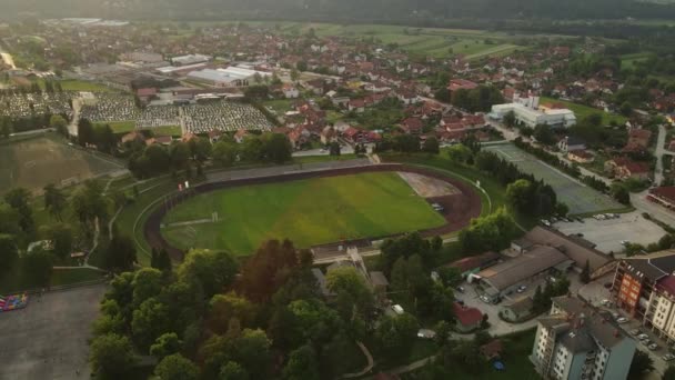 Aerial View of Football Stadium and Sports Complex in Bajina Basta Town, Serbia. Cityscape and People on Training, Orbit Drone Shot on Golden Hour Sunlight - Felvétel, videó