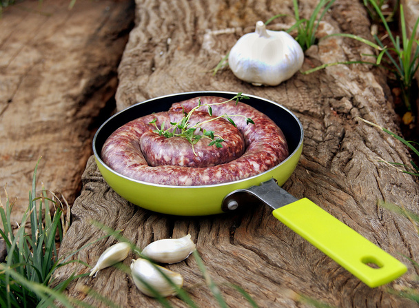 embutido de carne cruda en una sartén con ajo
 - Foto, Imagen