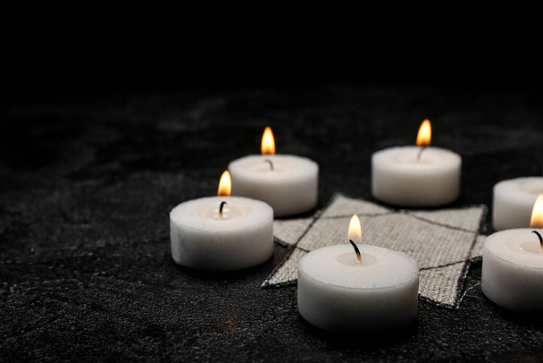 Burning candles and Jewish badge on dark background with space for text. International Holocaust Remembrance Day - 写真・画像