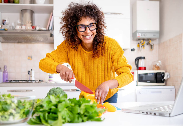 Cheerful black woman learning to cook at home watching online tutorial - Photo, Image