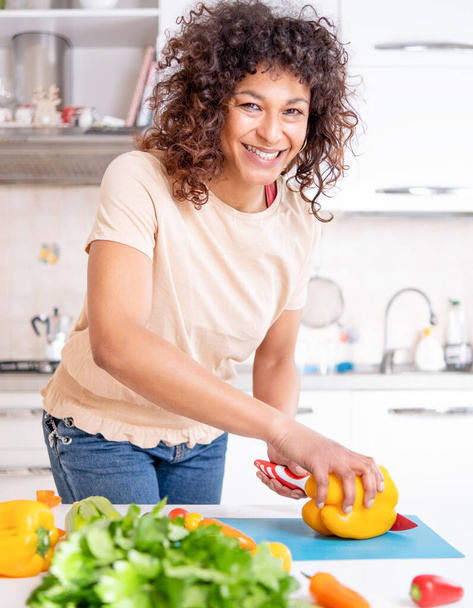 Cheerful black woman cooking at home looking a the camera - Fotoğraf, Görsel