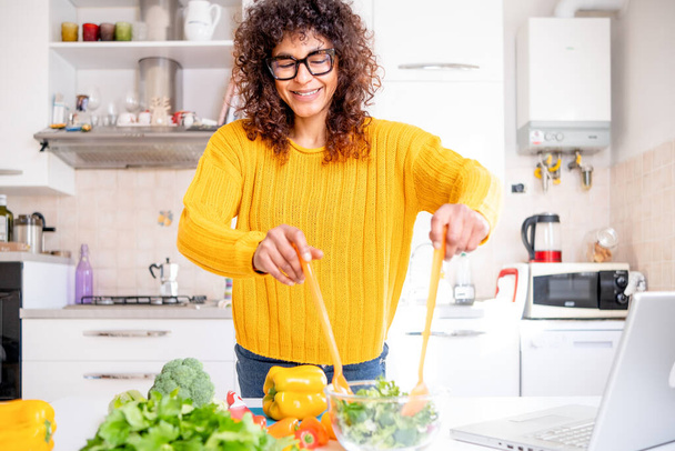 Happy black woman preparing healthy food vegetables salad at home - Foto, afbeelding