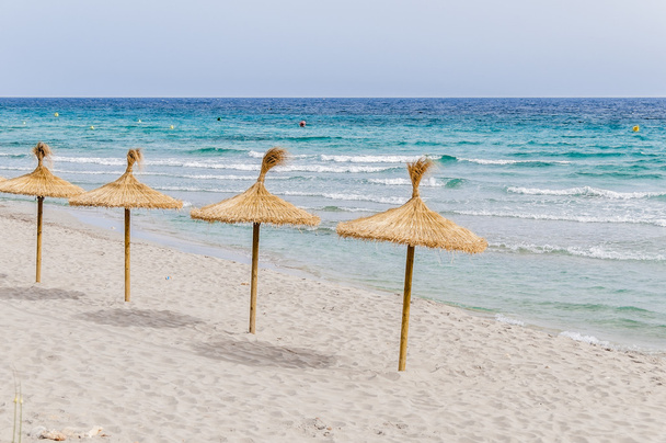 Parapluies de paille sur la plage de sable
. - Photo, image