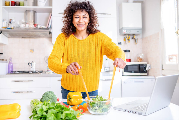 Happy black woman preparing healthy food vegetables salad at home - Photo, Image